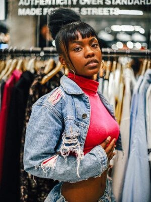 Stylish portrait of a Black woman in a denim jacket inside a clothing store.