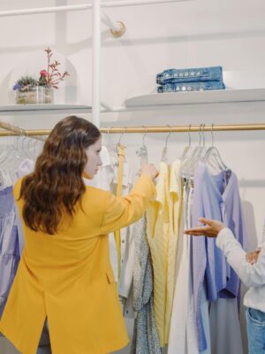 Two women browsing clothing in a stylish boutique, exploring various fashion options.